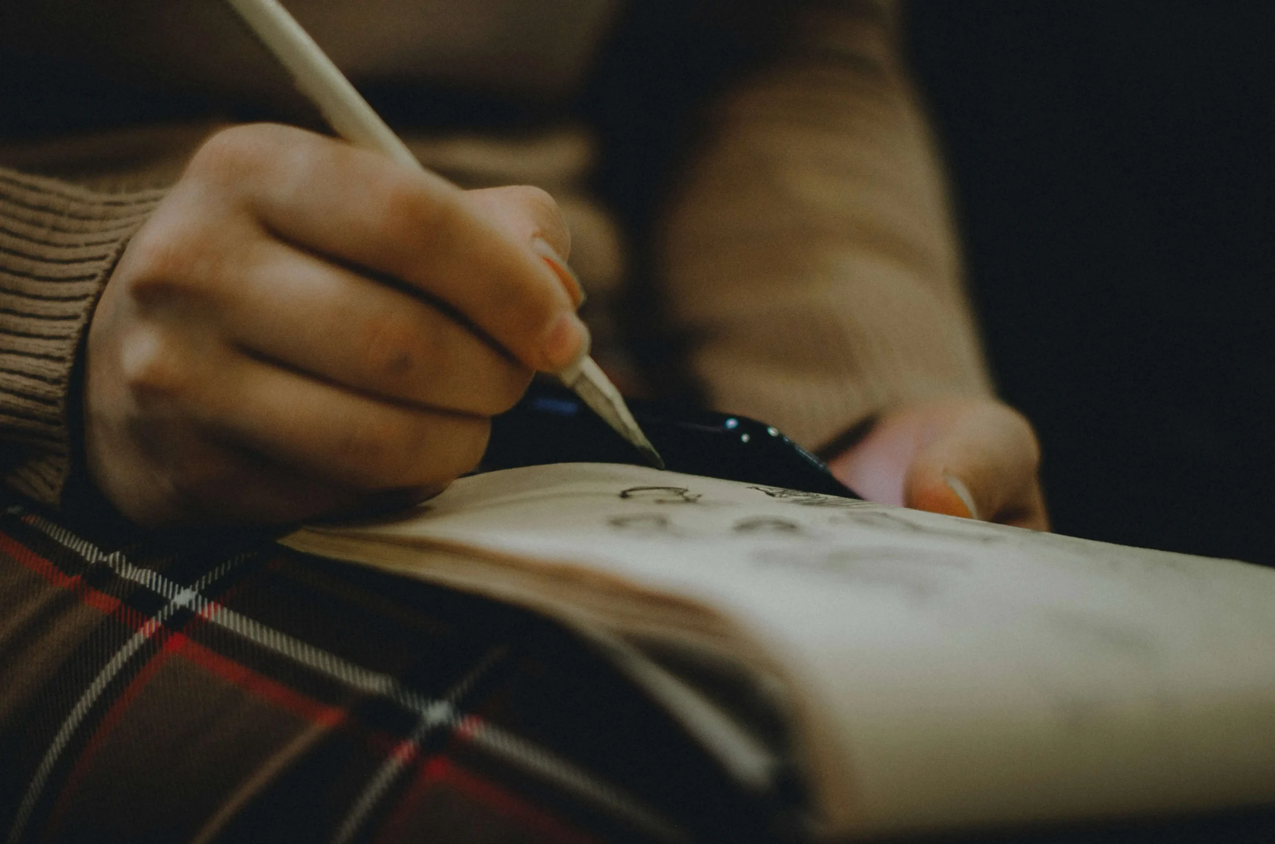 Hand writing on paper with an old-fashioned fountain pen in soft natural light