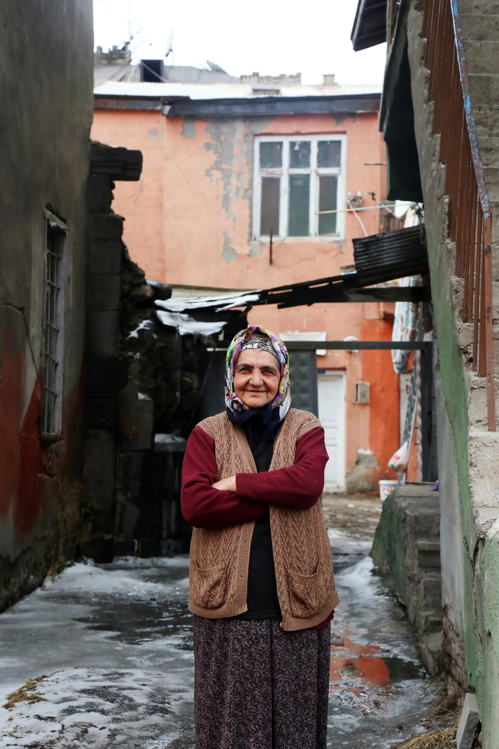 Elderly woman standing with arms folded and smiling warmly, radiating confidence and kindness
