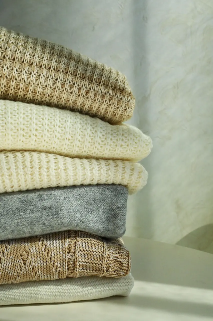 Stack of folded sweaters in soft earth tones symbolizing authentic fashion and personal style